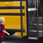 Little boy getting on school bus