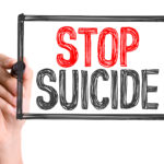 Hand with marker writing the word Stop Suicide